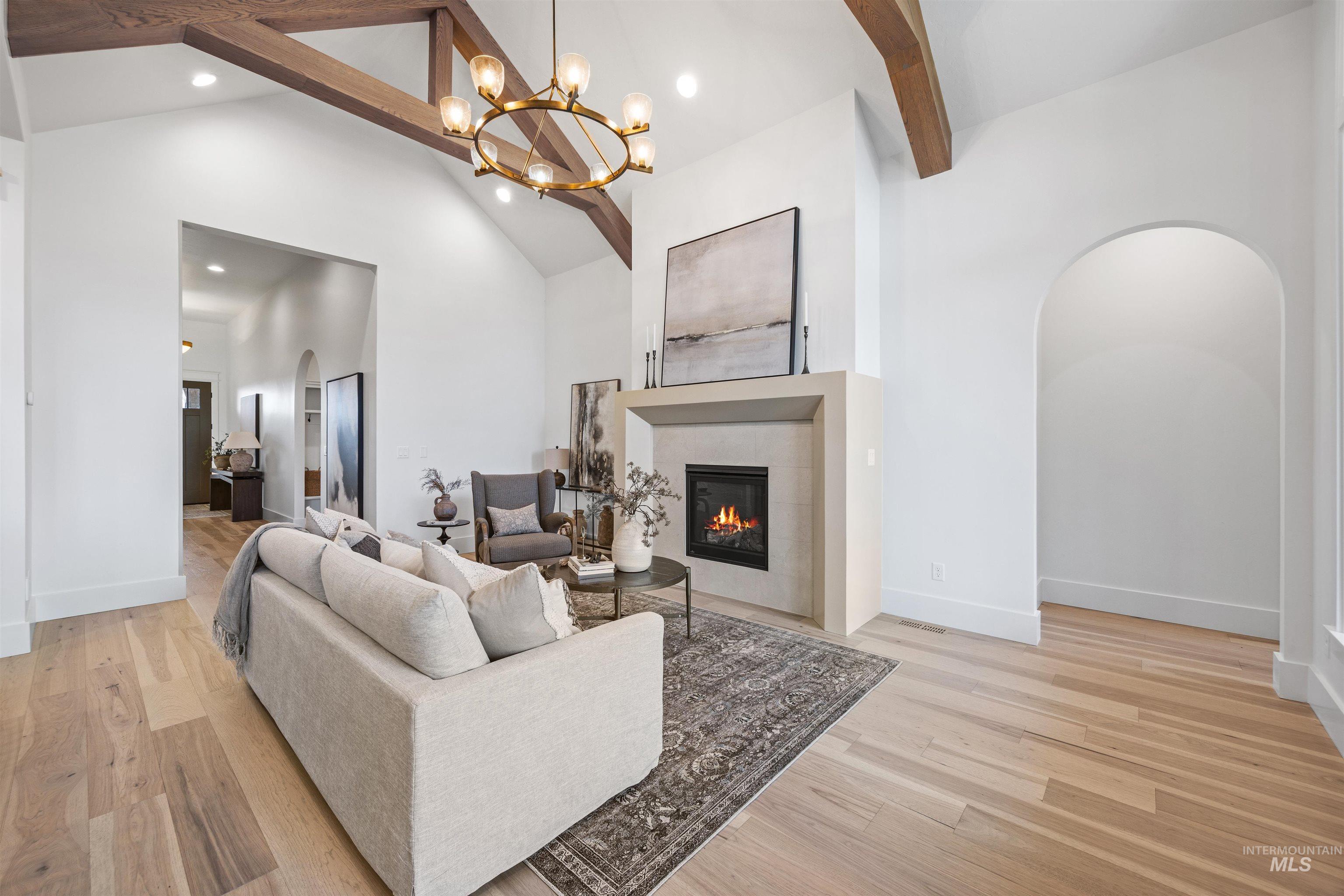 948 East Escalation Street Meridian, ID 83642 - Photo 12 of 44 Living room featuring arched walkways, light wood-style floors, vaulted ceiling, suspended lighting, and a fireplace