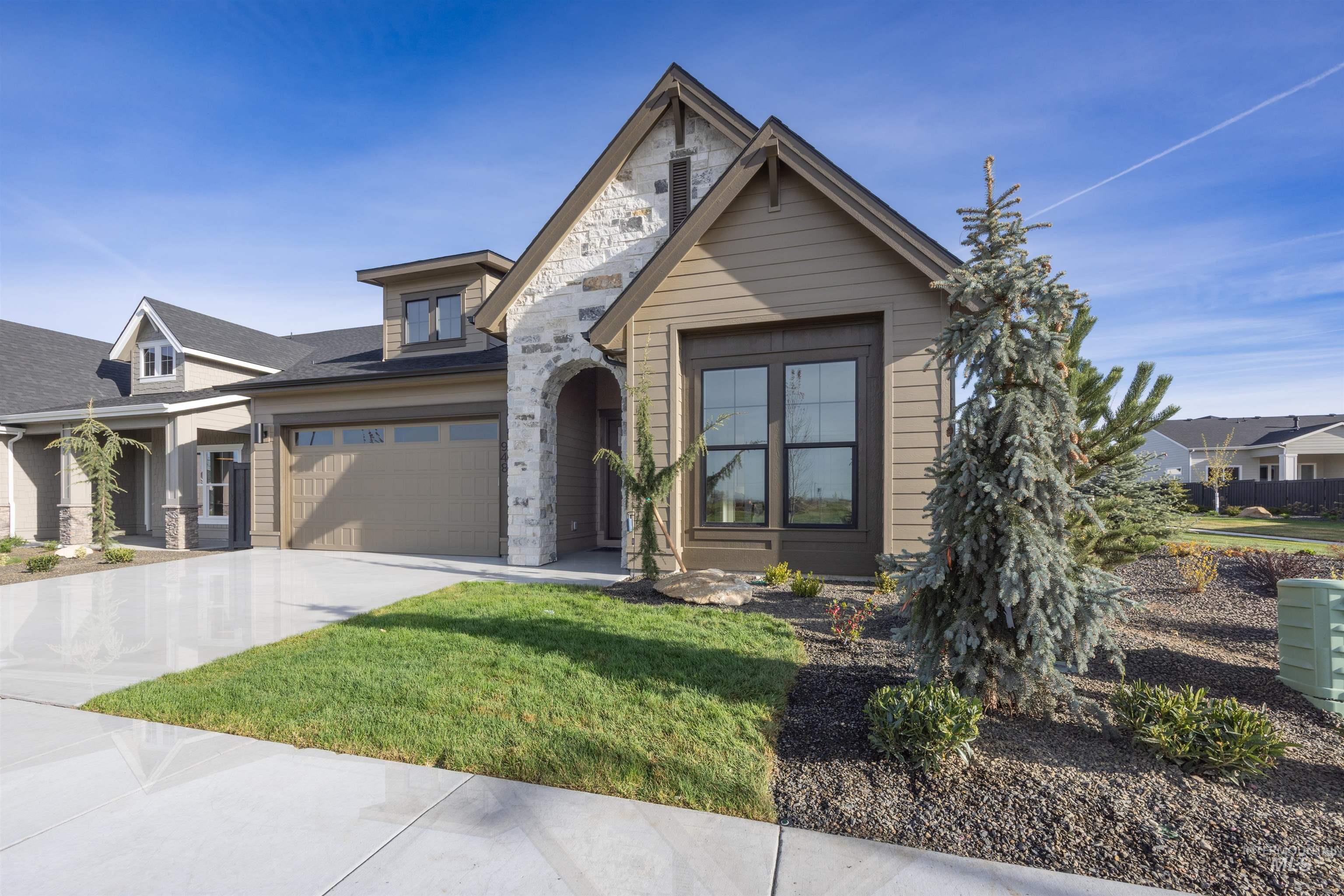 948 East Escalation Street Meridian, ID 83642 - Photo 2 of 44 View of front of house featuring concrete driveway, a front lawn, and stone siding