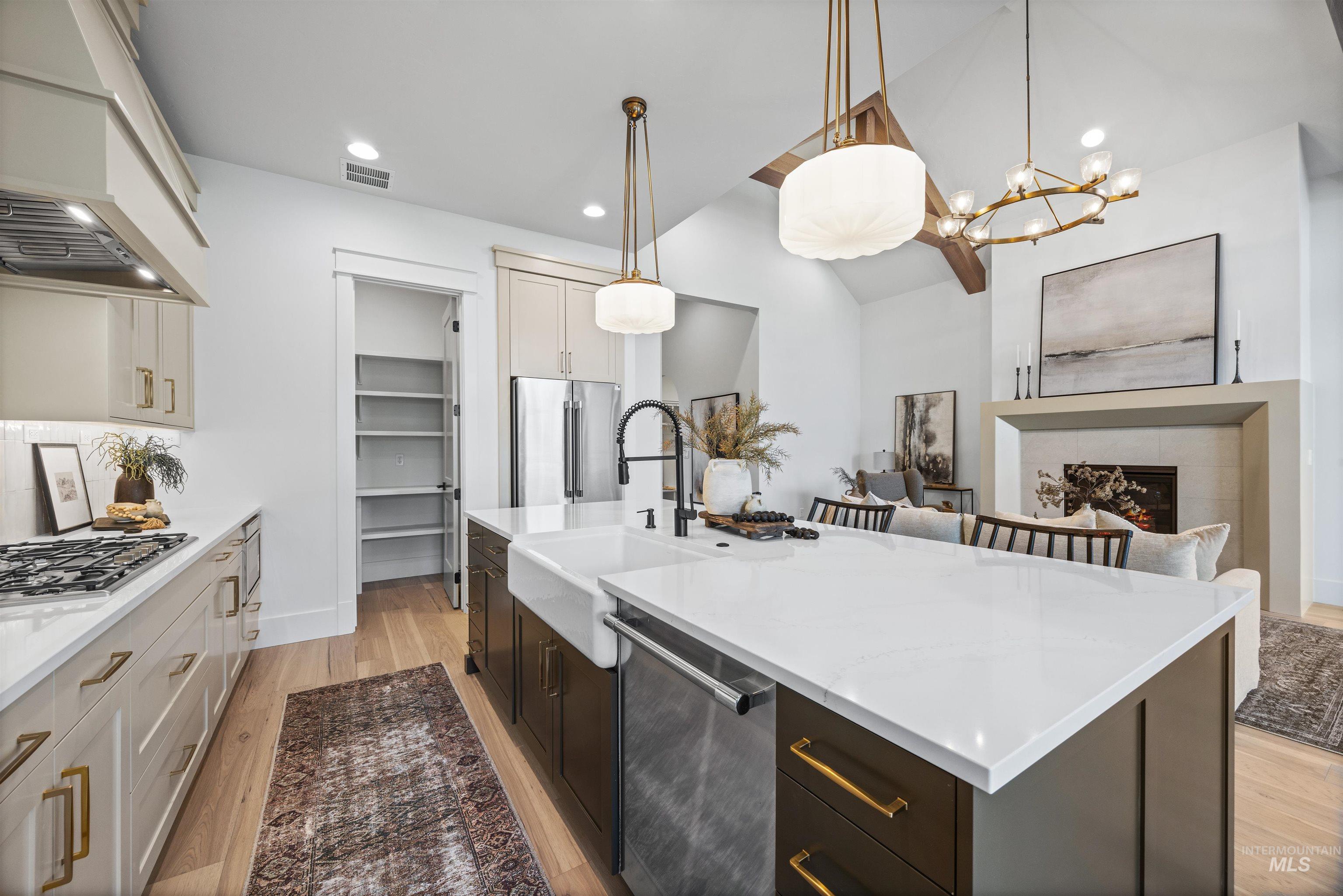 948 East Escalation Street Meridian, ID 83642 - Photo 21 of 44 Dual tone kitchen featuring two tone cabinetry, stainless steel appliances, light stone counters, a tiled fireplace, and light wood-type flooring