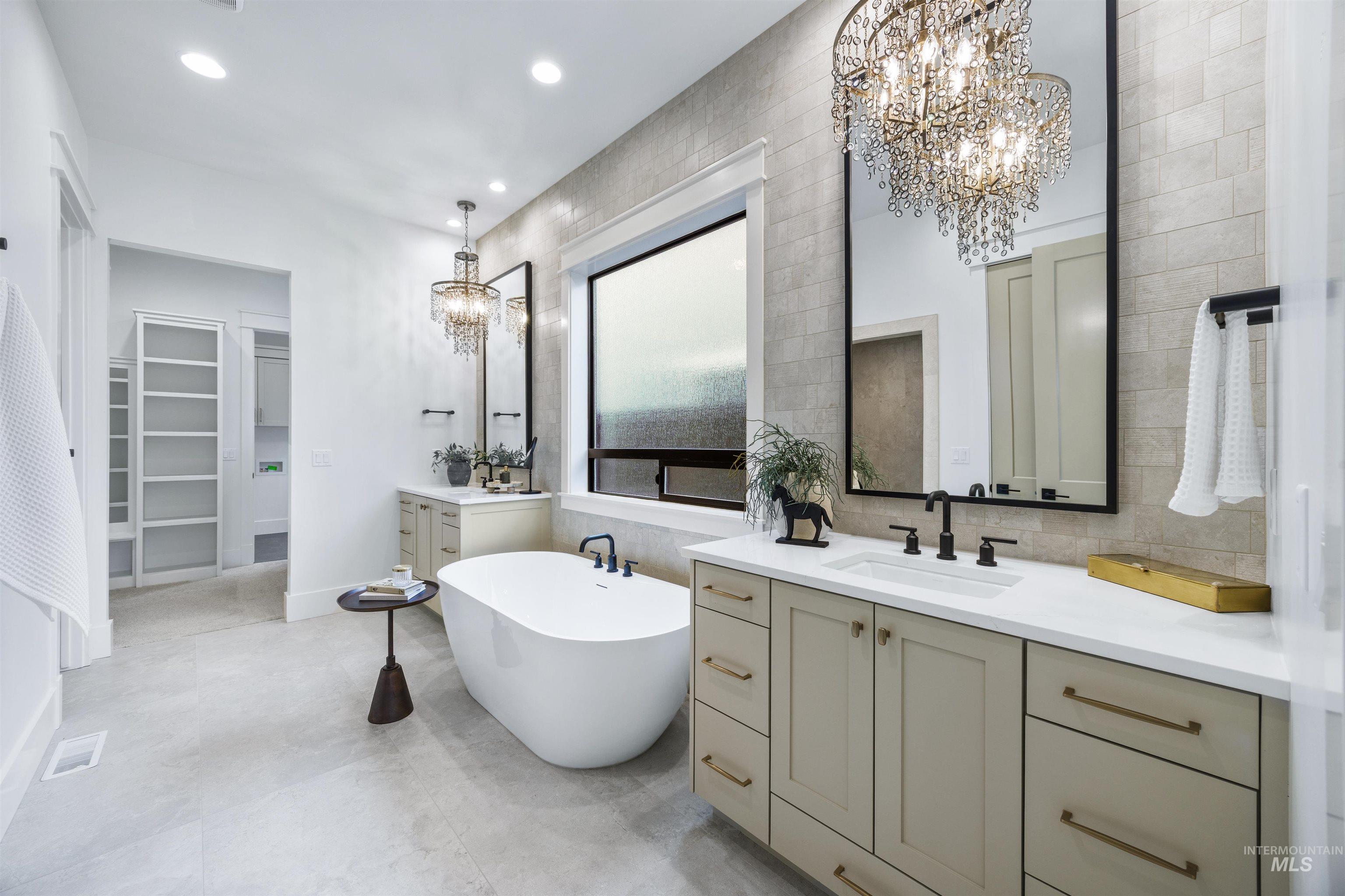 948 East Escalation Street Meridian, ID 83642 - Photo 25 of 44 Full bathroom with a chandelier, a spacious closet, two vanities, a freestanding bath, and tile walls