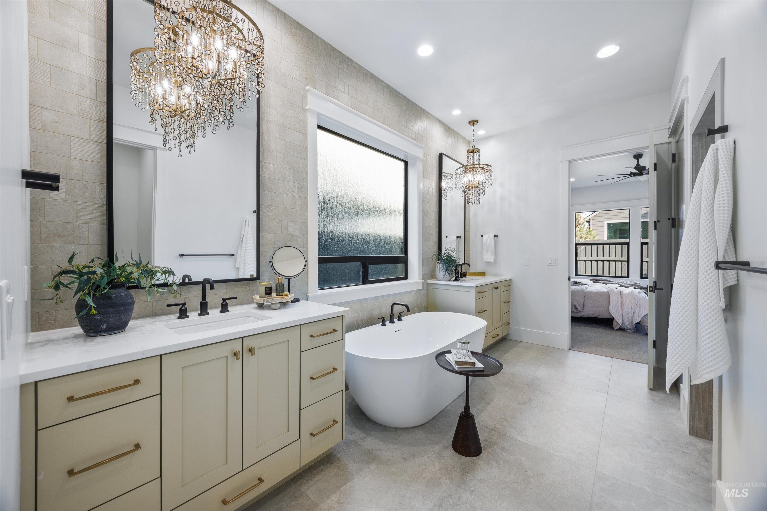 948 East Escalation Street Meridian, ID 83642 - Photo 28 of 44 Ensuite bathroom with suspended lighting, two vanities, tile walls, and a soaking tub