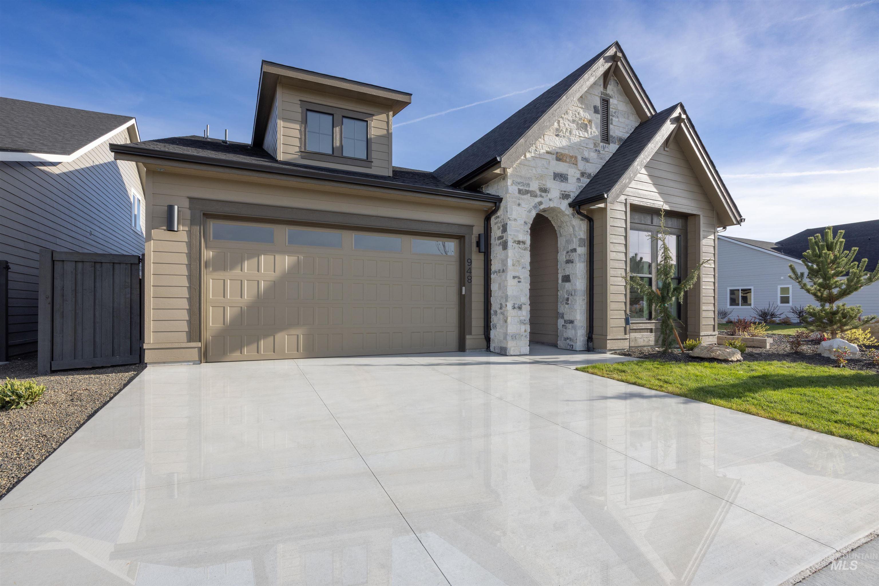 948 East Escalation Street Meridian, ID 83642 - Photo 42 of 44 View of front of house featuring stone siding, concrete driveway, and an attached garage