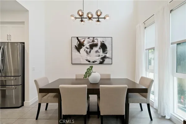 a kitchen with stainless steel appliances a dining table chairs and refrigerator