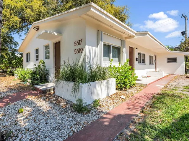a front view of a house with a yard and potted plants