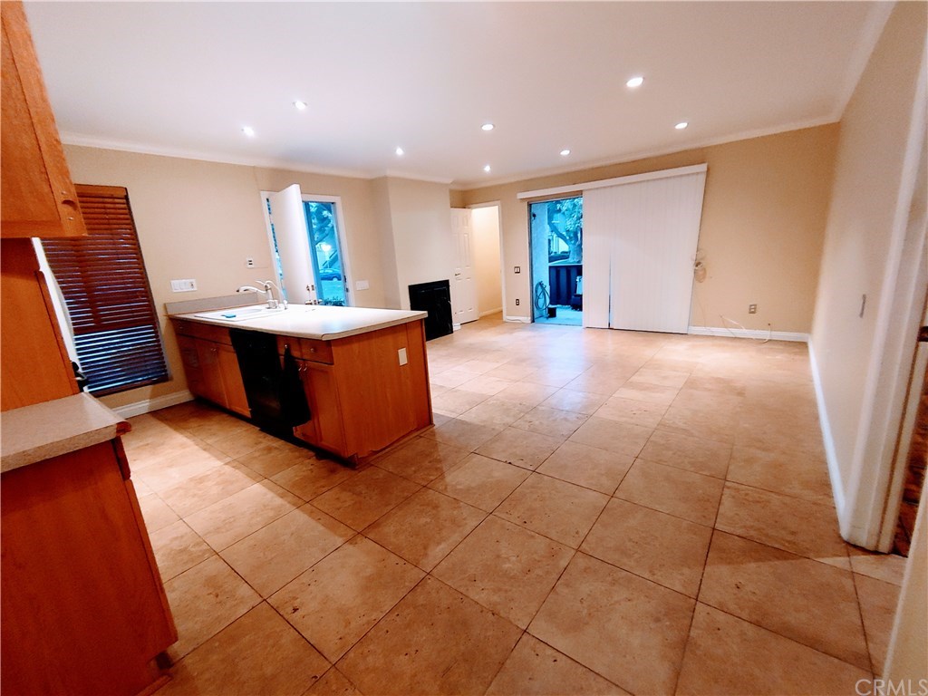 Custom Wood kitchen cabinets, travertine floors. View from dinette area from the left- kitchen window, entry door, fireplace (not hooked up do not use), storage closet, sliding glass doors to patio