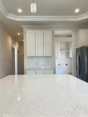 a large white kitchen with kitchen island sink refrigerator and cabinets