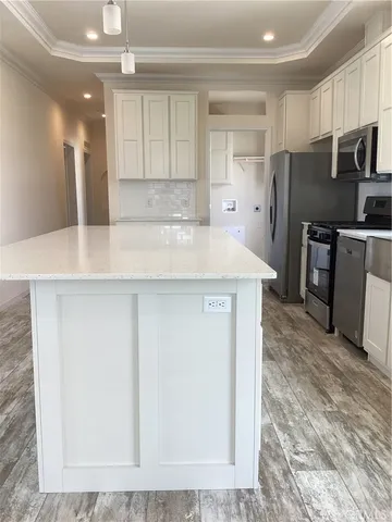 a kitchen with kitchen island a counter top space cabinets and stainless steel appliances