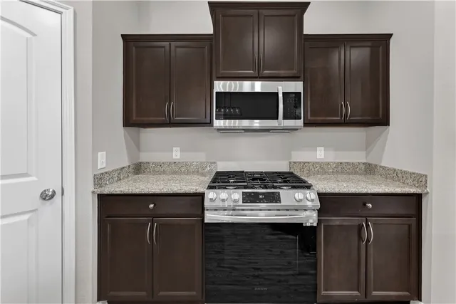a kitchen with granite countertop cabinets stove and microwave