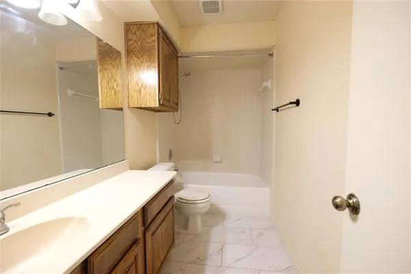 a bathroom with a granite countertop sink a toilet and shower