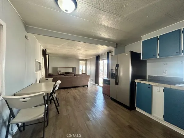 a living room with stainless steel appliances furniture a kitchen view and a refrigerator