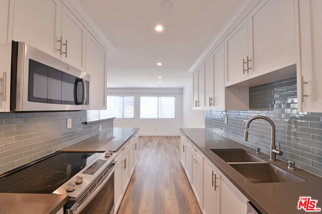 a kitchen with granite countertop a sink stainless steel appliances and cabinets