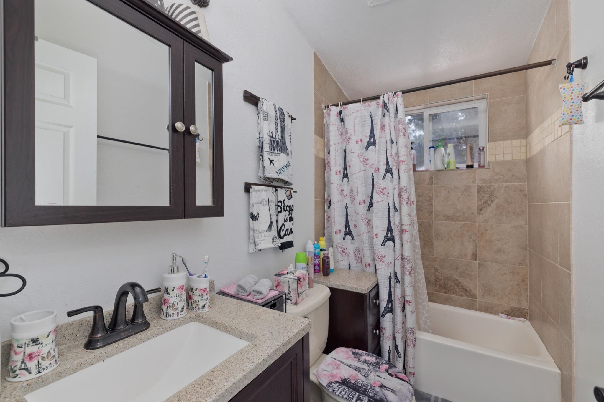 100 Ski Trails Road, Unit 10 Mammoth Lakes, CA 93546 - Photo 14 of 26 Built-in dark wood finish medicine cabinet, vanity with integrated sink and dark bronze faucet, and tiled shower surround with accent band