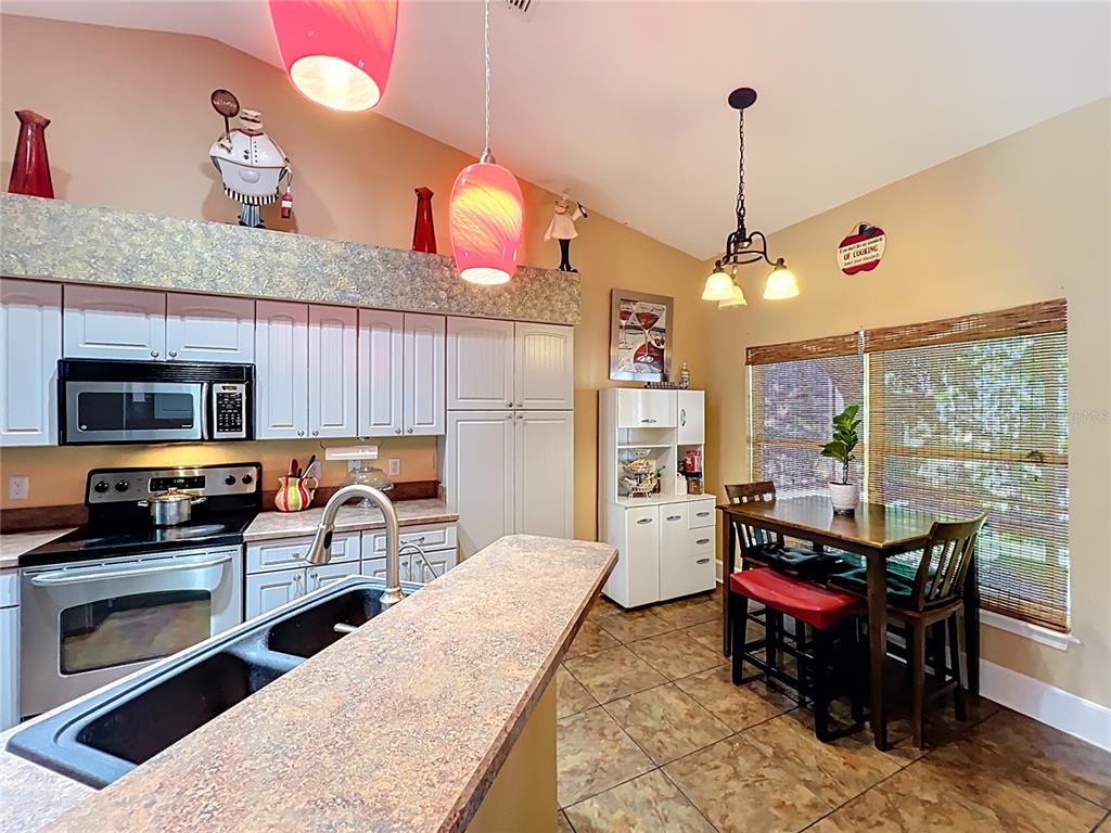 1312 Perkins Road Orlando, FL 32809 - Photo 25 of 80 a kitchen with stainless steel appliances kitchen island granite countertop a stove top oven a sink dishwasher a dining table and chairs with wooden floor