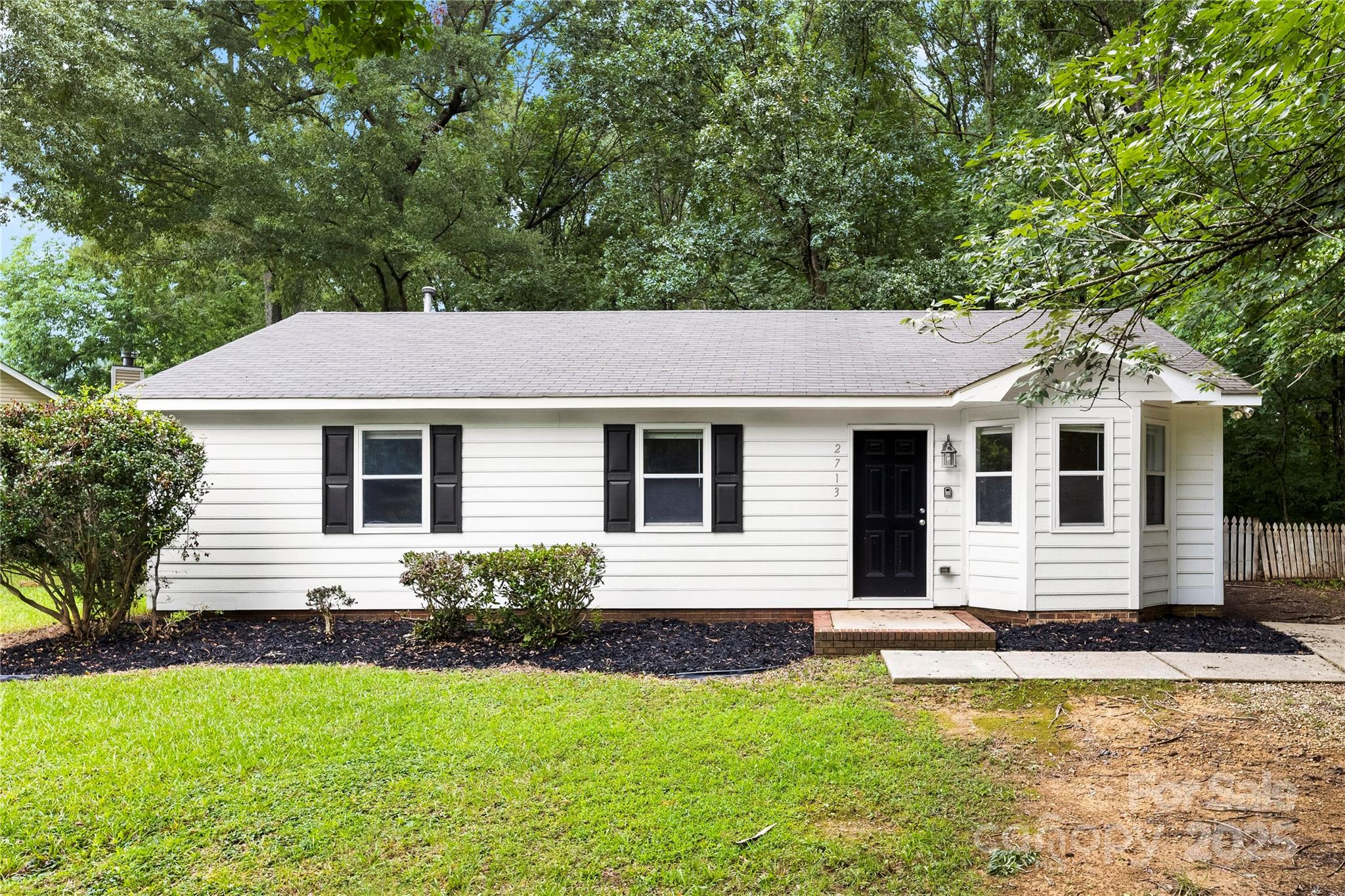 a front view of house with yard and trees in the background