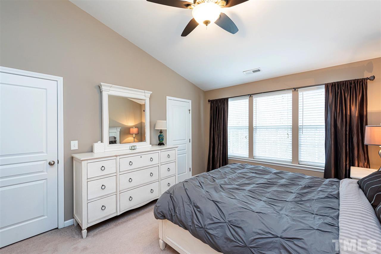 7749 Winners Edge Street Raleigh, NC 27617 - Photo 11 of 29 a bedroom with a large bed and a dresser