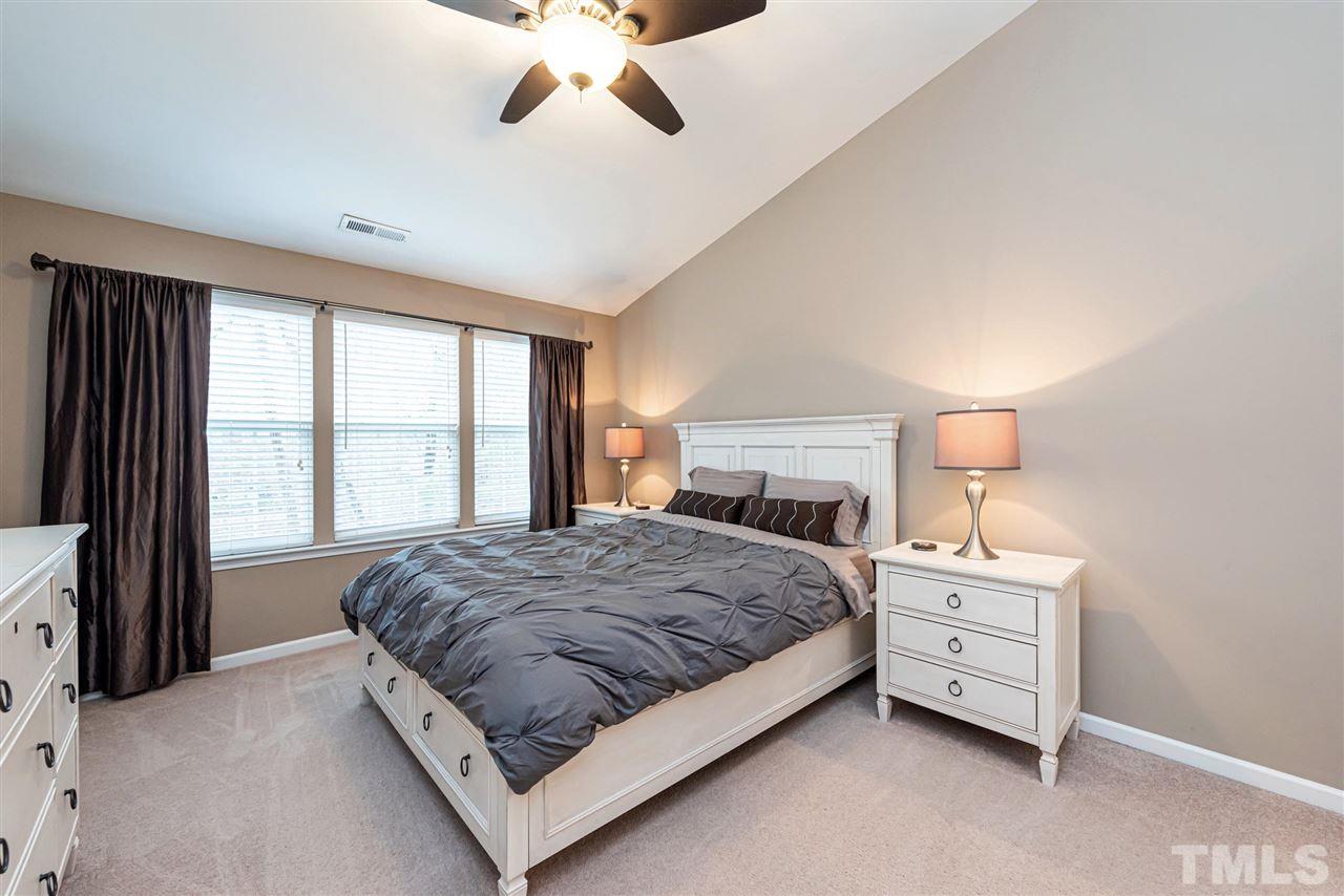 7749 Winners Edge Street Raleigh, NC 27617 - Photo 10 of 29 a bedroom with a large bed and a chandelier