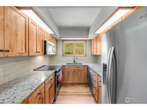 a kitchen with stainless steel appliances granite countertop a sink a stove and a refrigerator