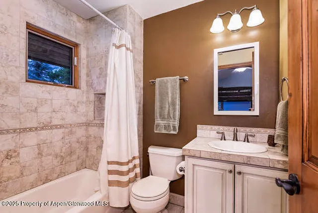a bathroom with a granite countertop toilet a sink and a mirror