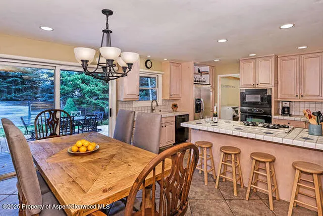 a kitchen with stainless steel appliances granite countertop a dining table chairs and granite counter tops