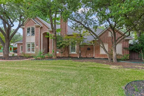 a front view of a house with a garden and trees