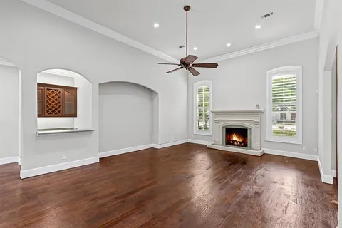 a view of an empty room with wooden floor fireplace and a window