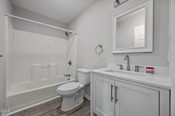 a bathroom with a toilet sink vanity granite and shower
