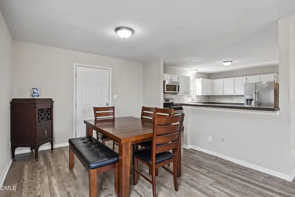 a kitchen with stainless steel appliances kitchen island granite countertop a table chairs in it and white cabinets