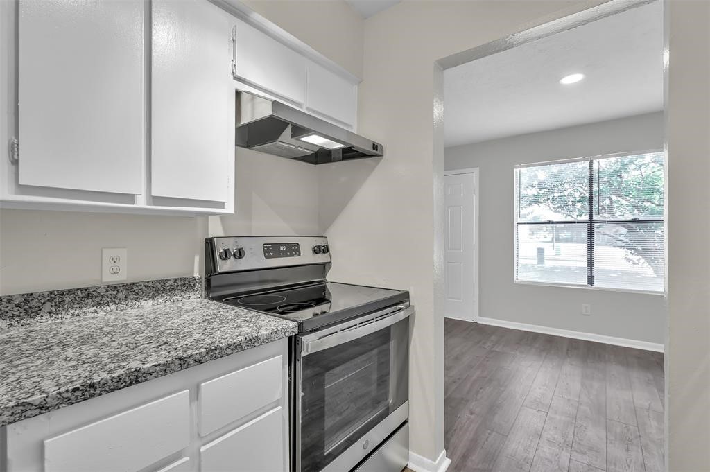 a kitchen with granite countertop cabinets stainless steel appliances and a wooden floor