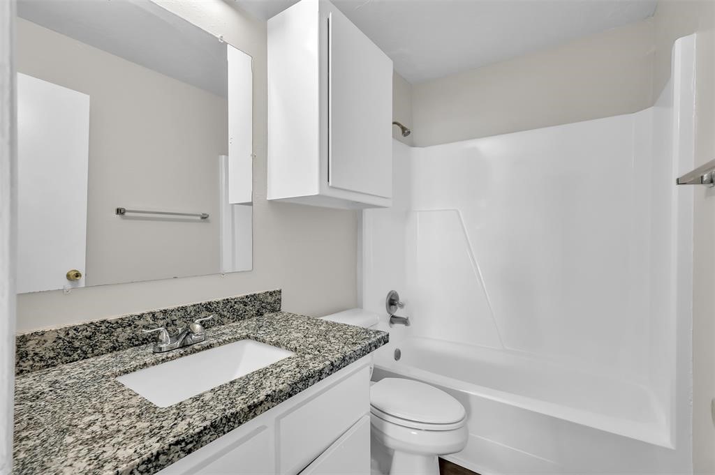 900 Holly Drive, Unit 13 Conroe, TX 77301 - Photo 11 of 12 a bathroom with a granite countertop sink a toilet and bathtub