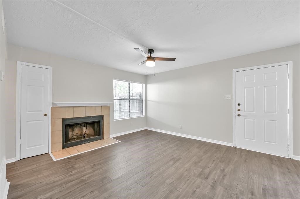 900 Holly Drive, Unit 13 Conroe, TX 77301 - Photo 5 of 12 an empty room with fireplace wooden floor and windows