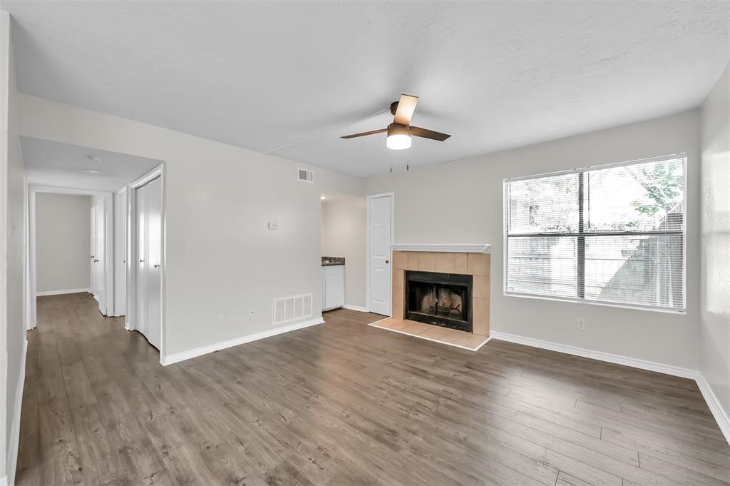 900 Holly Drive, Unit 13 Conroe, TX 77301 - Photo 10 of 12 an empty room with wooden floor fireplace and windows