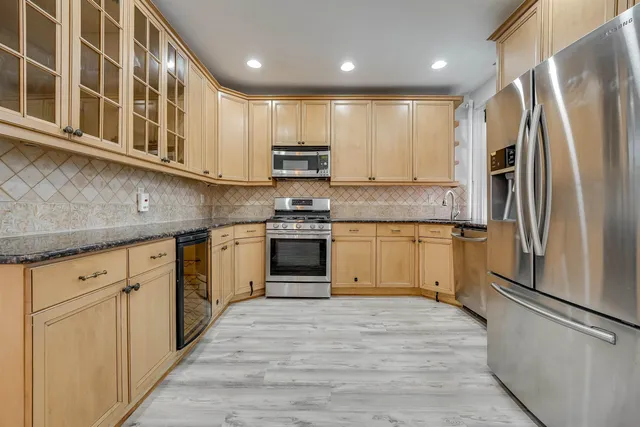 a kitchen with stainless steel appliances granite countertop a refrigerator and a stove top oven