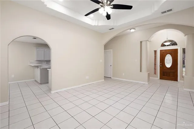 a view of an empty room with chandelier fan