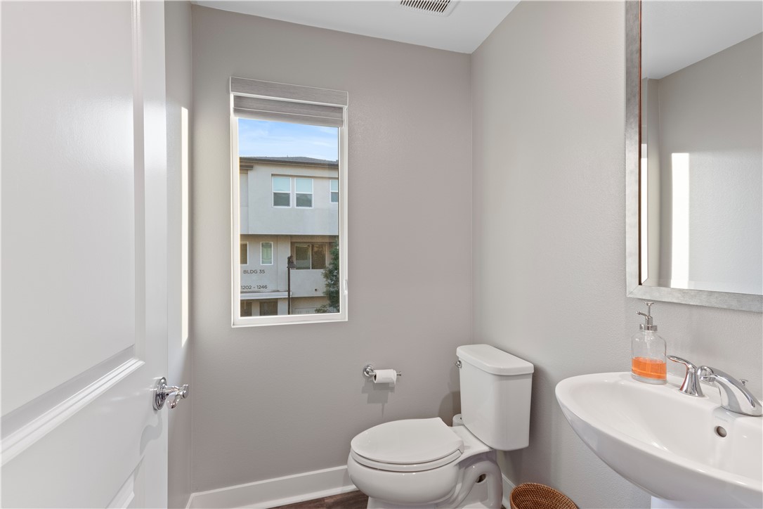1215 West Bushell Street Anaheim, CA 92805 - Photo 10 of 24 a bathroom with a toilet a sink a mirror and vanity