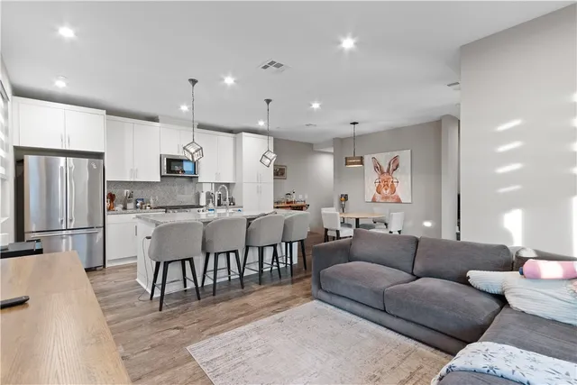 a living room kitchen with a dining table wooden floor and stainless steel appliances