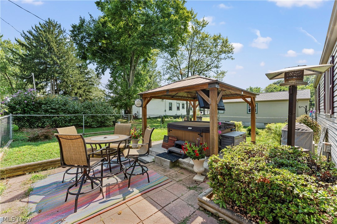 7000 Navarre Road Southwest Massillon, OH 44646 - Photo 11 of 22 This property features a paved patio area with an outdoor dining table and chairs, and a covered hot tub