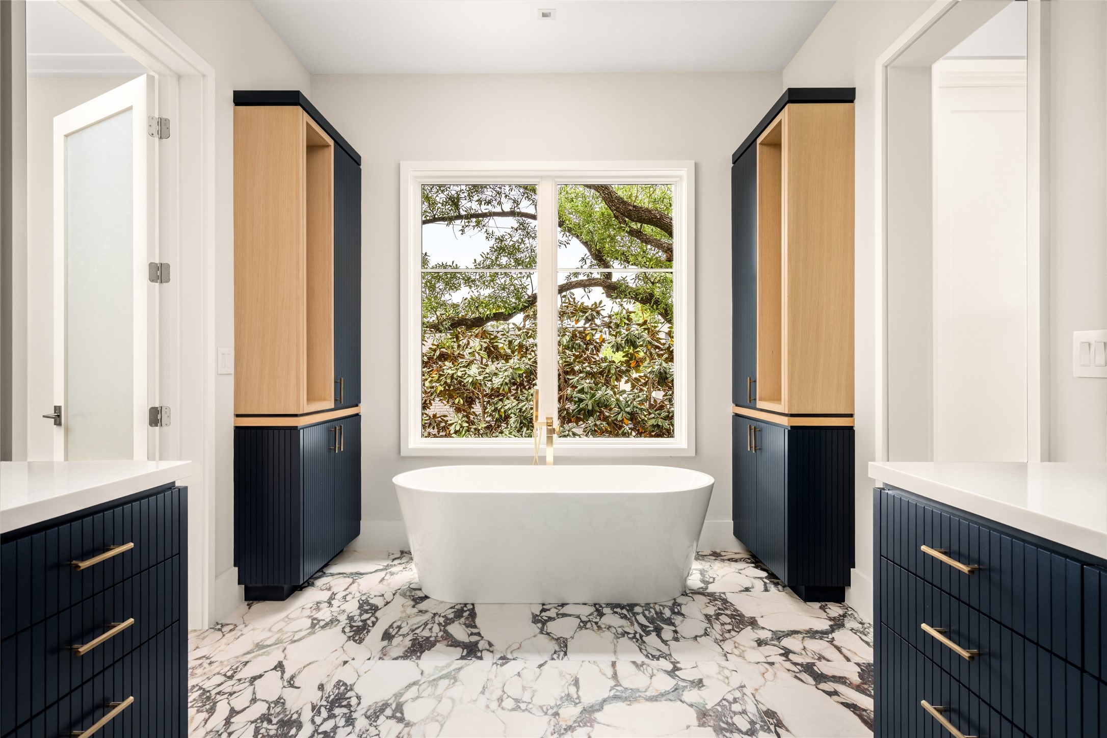 4006 Overbrook Lane Houston, TX 77027 - Photo 28 of 50 A spa-like moment unfolds with a freestanding soaking tub positioned beneath a window of greenery and framed by architectural symmetry.
