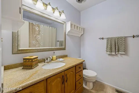 a bathroom with a granite countertop sink toilet and a mirror