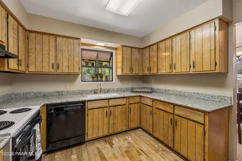 a kitchen with stainless steel appliances granite countertop wooden cabinets a sink and dishwasher a stove top oven with wooden floor