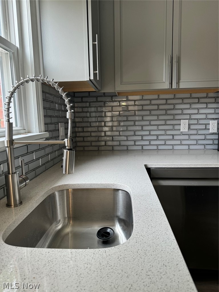 5671 Wellington Road Cleveland, OH 44124 - Photo 8 of 26 Room details featuring decorative backsplash, dishwasher, light stone counters, and gray cabinetry