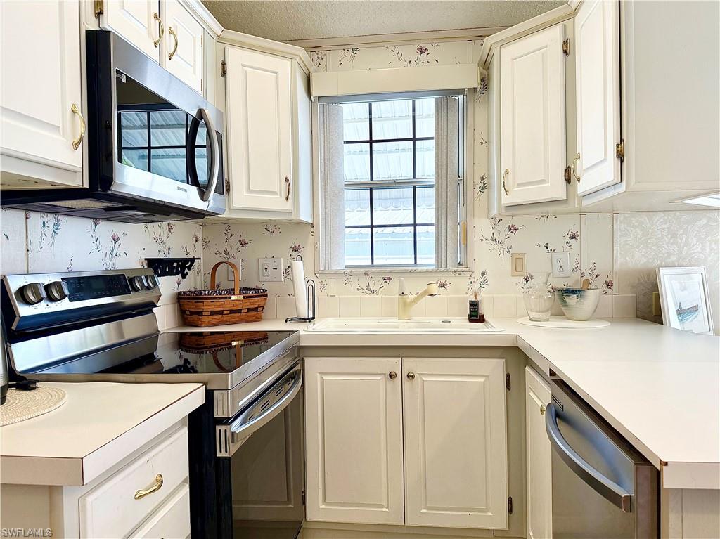 233 Cattleya Refuge, Unit 233 Naples, FL 34114 - Photo 14 of 48 a kitchen with stainless steel appliances granite countertop a sink stove and cabinets