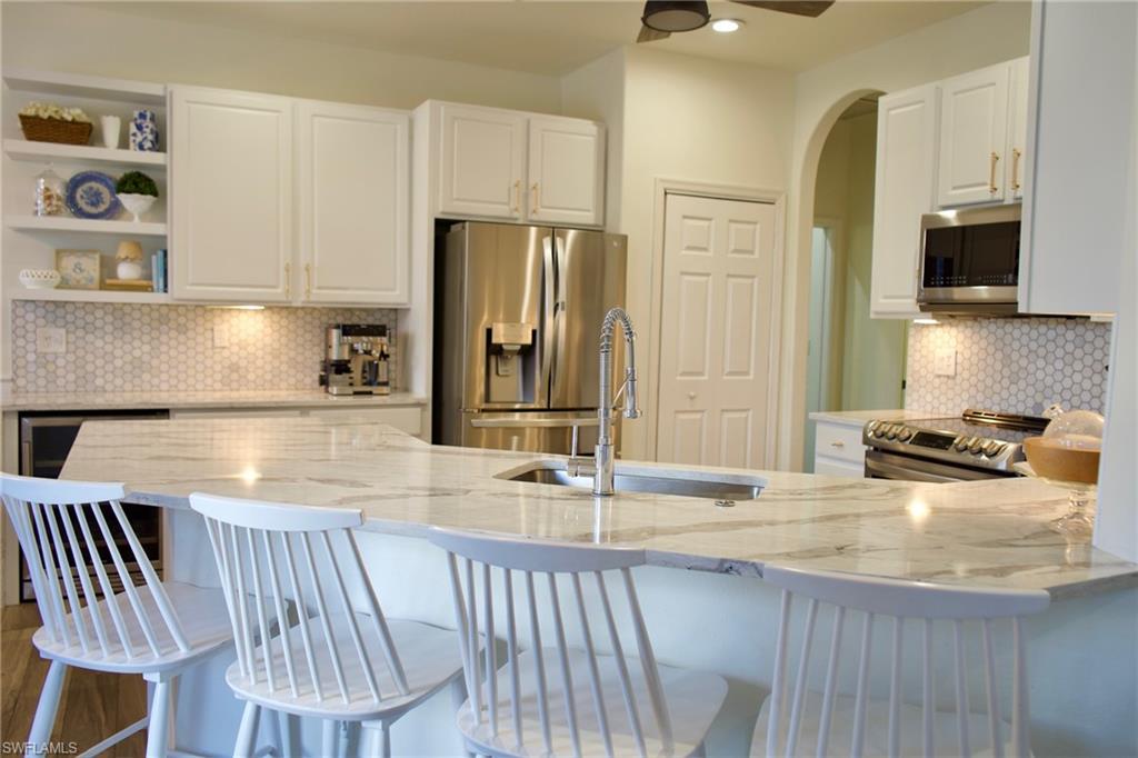 3944 Ruxton Road Naples, FL 34116 - Photo 6 of 27 a kitchen with stainless steel appliances granite countertop a sink table and chairs