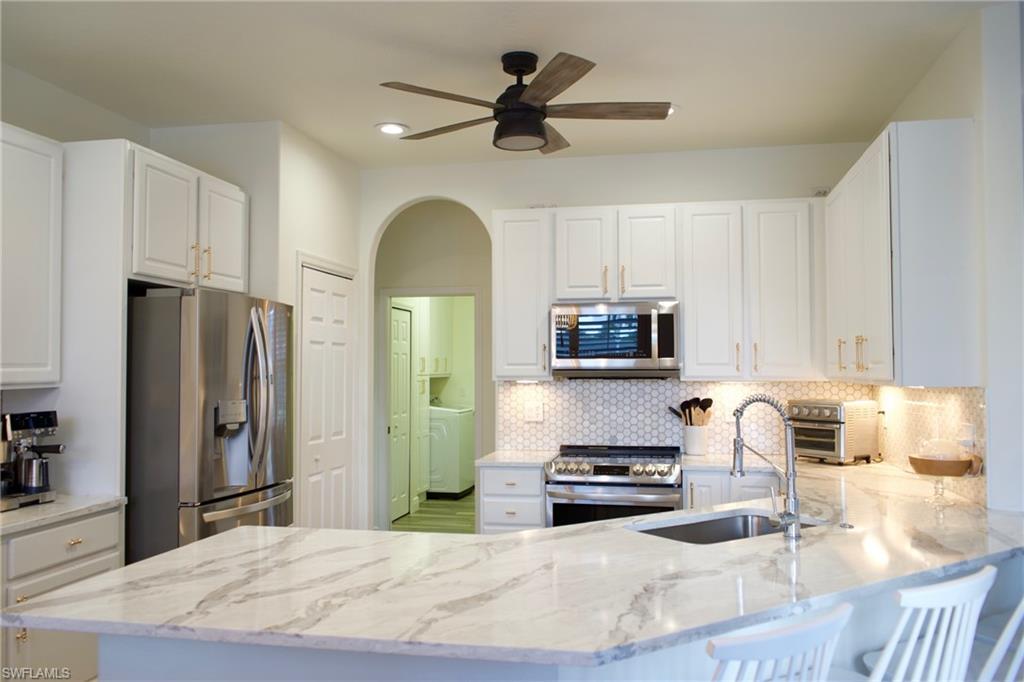 3944 Ruxton Road Naples, FL 34116 - Photo 9 of 27 a kitchen with stainless steel appliances kitchen island granite countertop a refrigerator and a stove top oven