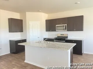 a kitchen with kitchen island granite countertop a sink a stove top oven a refrigerator and a sink