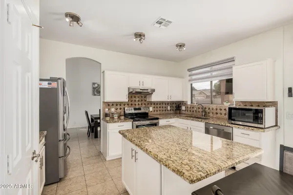 a kitchen with stainless steel appliances granite countertop a sink stove and refrigerator
