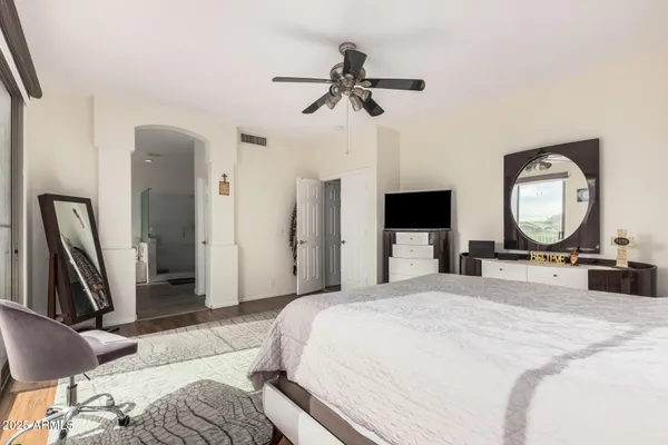 a bedroom with a bed a mirror on dresser and a flat screen tv