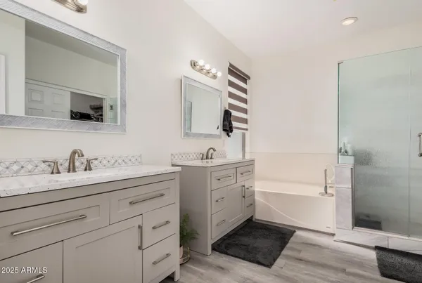 a bathroom with double vanity sink a mirror and a bathtub