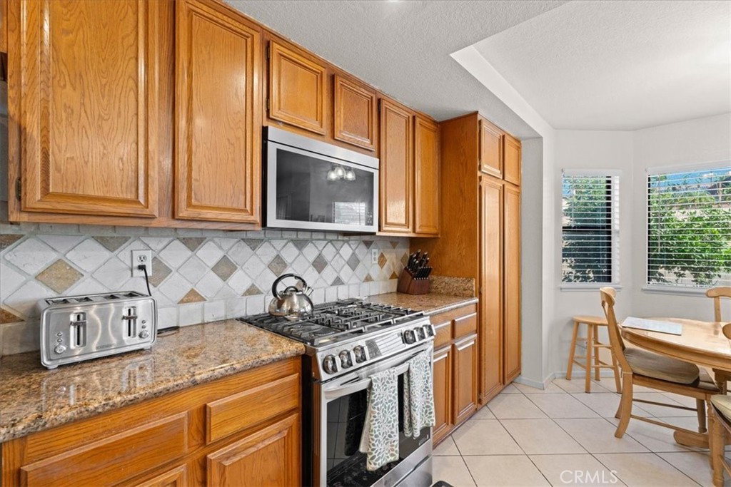 10536 Deerfield Drive Rancho Cucamonga, CA 91701 - Photo 11 of 28 a kitchen with stainless steel appliances granite countertop a stove a sink and a microwave