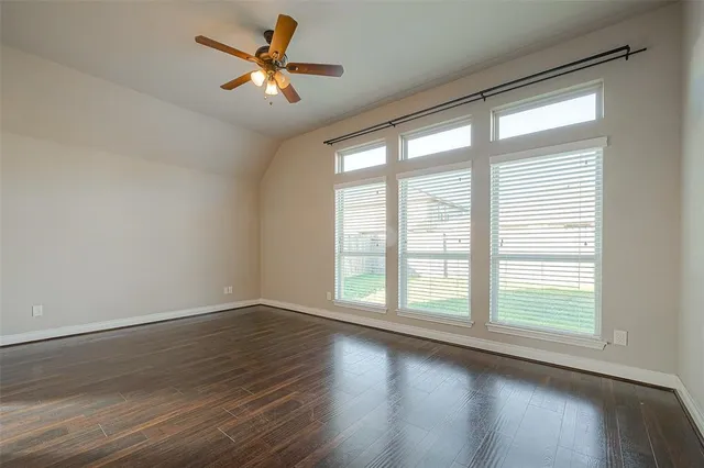 an empty room with wooden floor and a ceiling fan