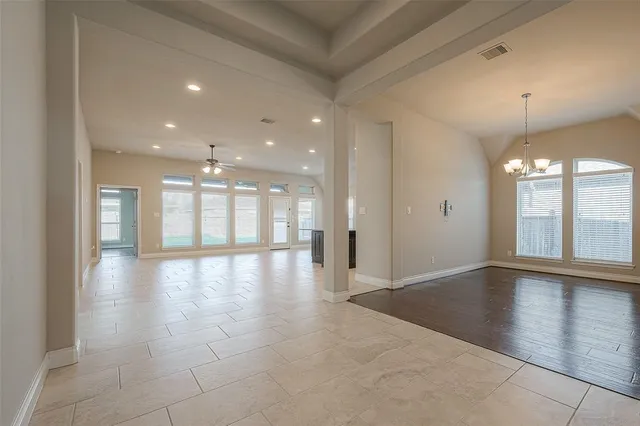 a view of an empty room with wooden floor and a kitchen
